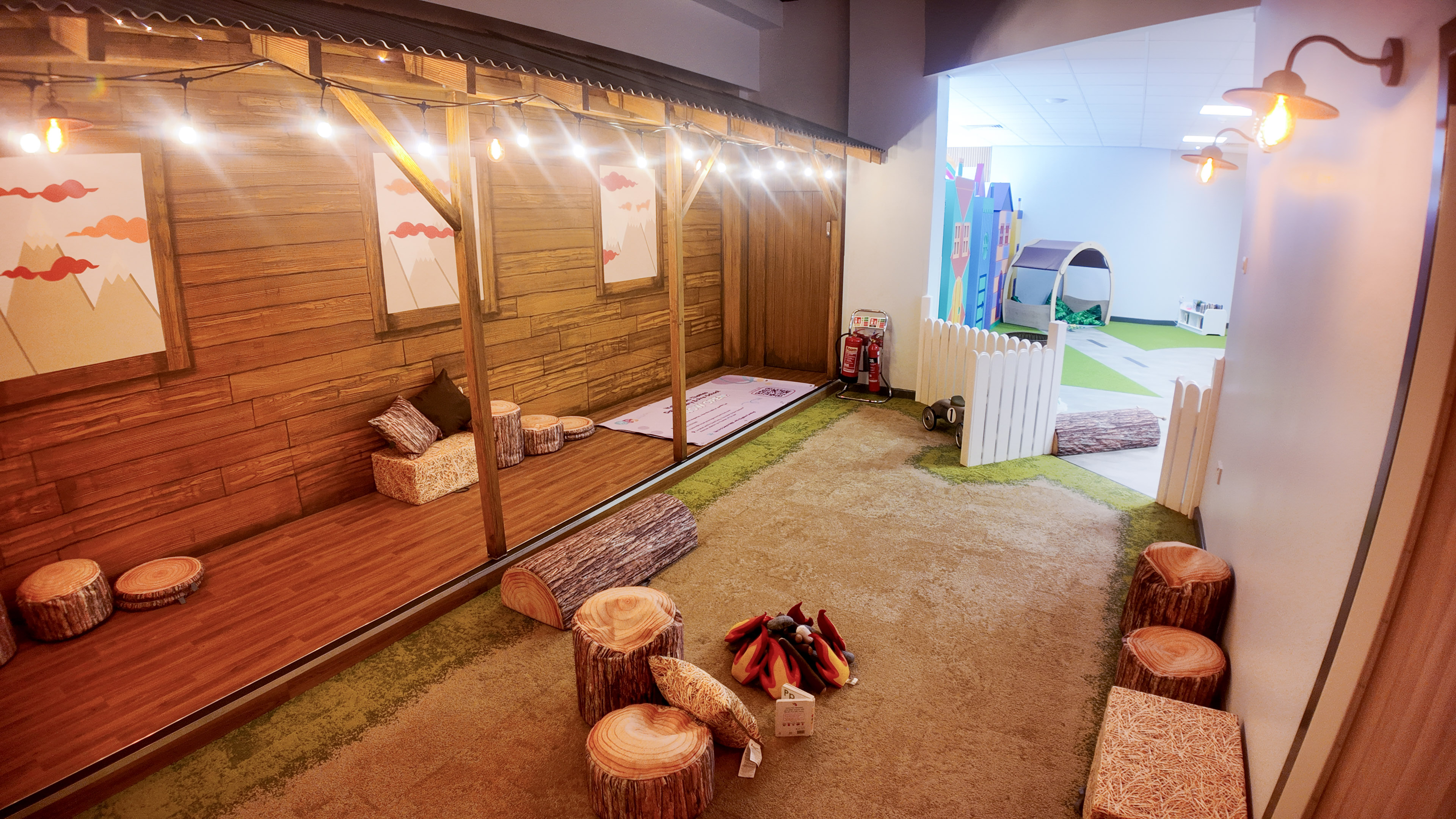 Cosy campfire-themed storytelling nook with log stools and fairy lights